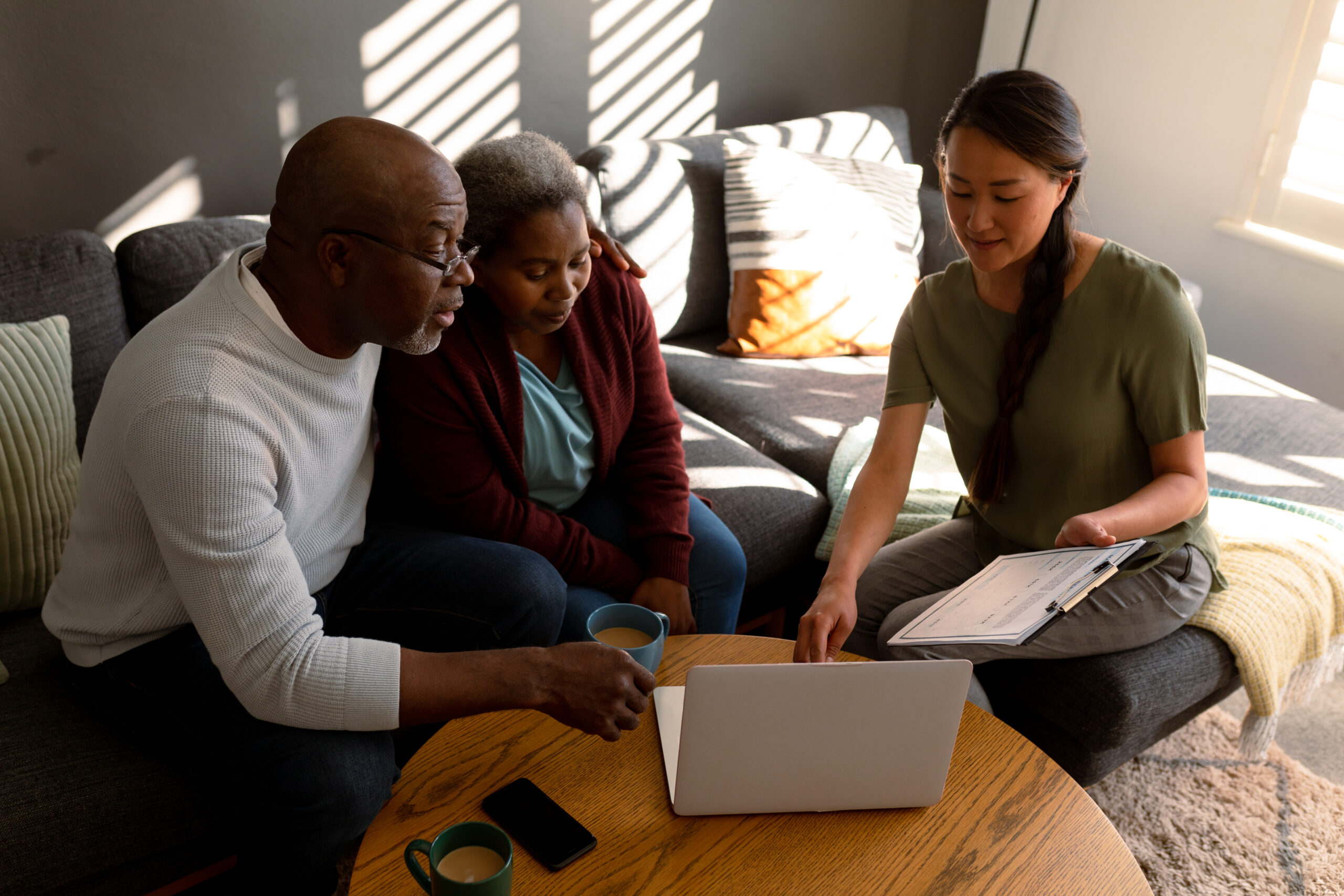 African american senior couple having meeting with asian female financial advisor at home. retirement lifestyle, elderly support and spending time at home.